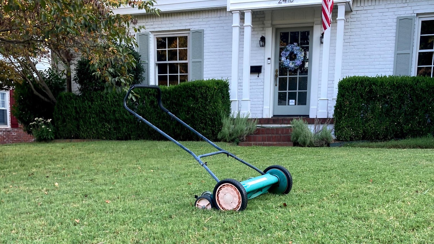 Reel mower on lawn in front of house